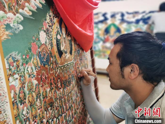 圖為更登才讓的徒弟繪畫唐卡?！?zhí)砀?攝